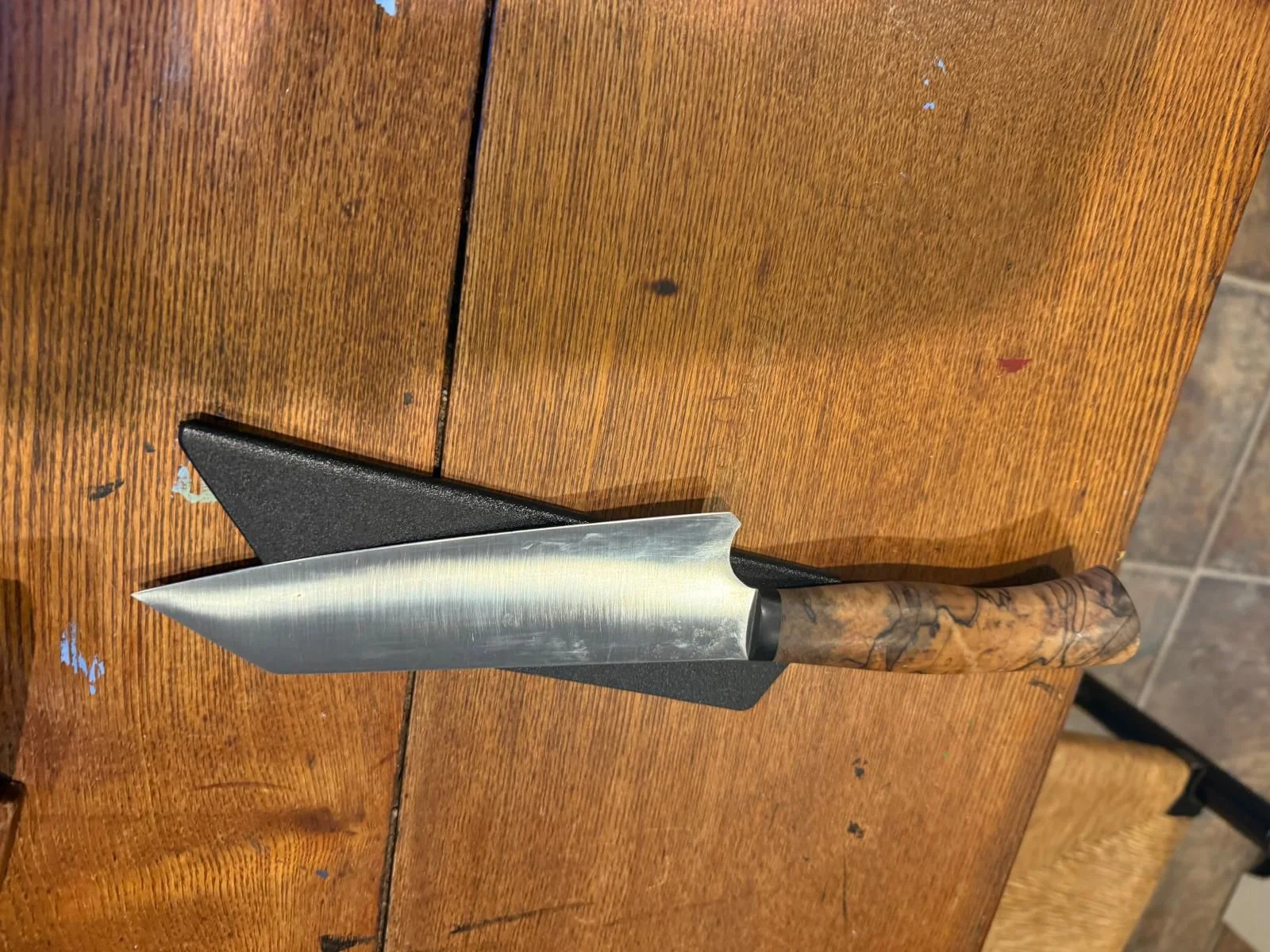 This knife was a collaboration between Tony and his wife, Amber, a master Craftswoman in her own right, with input from 2 award-winning Chefs. It is my go-to knife for kitchen work. Made from Swedish Sandvik 14C28N: Blade Length overall: 7” Cutting surface: 6” 1/2”: Tanto style tip. Handle Material is a beautiful, stabilized spalted Maple with a very comfortable, slight palm swell, and comes with a lined nylon drawer sheath.